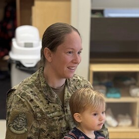 un parent militaire avec son enfant sur les genoux à l'heure de la collation